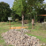 Lesesteinhaufen mit Infotafel umgeben von Wiese und Bäumen Lesesteinhaufen mit Infotafel umgeben von Wiese und Bäumen