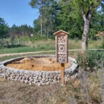 Sandarium in Lesesteinfassung, daneben ein Insektenhotel Sandarium in Lesesteinfassung, daneben ein Insektenhotel