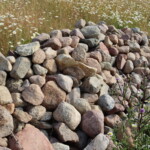 Länglicher Haufen aus Steinen in einer Wiese