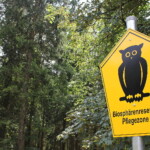 Im Vordergunf ein Biosphärenreservat-Pflegezone-Schild, im Hintergrund ist Wald zu sehen