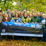Eine Gruppe von Menschen steht vor herbstlicher Naturkulisse zu einem gemeinsamen Foto zusammen, die Menschen in der ersten Reihe halten ein Banner der Initiative „Wildnis in Deutschland“ in den Händen. Eine Gruppe von Menschen steht vor herbstlicher Naturkulisse zu einem gemeinsamen Foto zusammen, die Menschen in der ersten Reihe halten ein Banner der Initiative „Wildnis in Deutschland“ in den Händen.