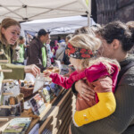 Eine Umweltpraktikantin steht an einem Infostand im Gespräch mit Besuchenden Eine Umweltpraktikantin steht an einem Infostand im Gespräch mit Besuchenden