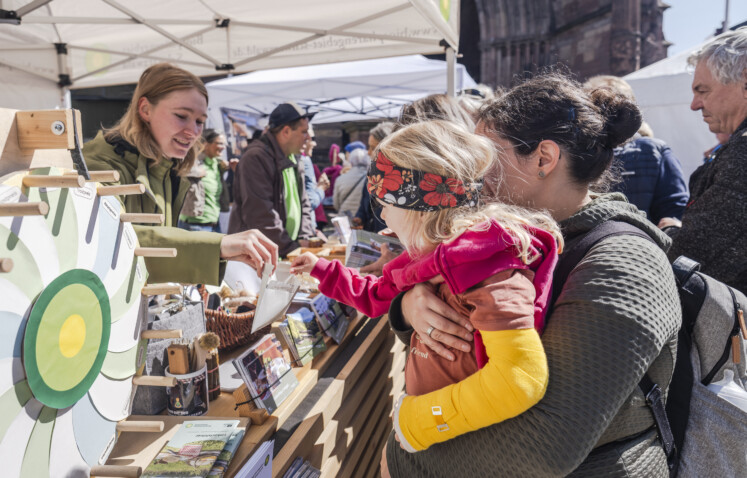 Eine Umweltpraktikantin steht an einem Infostand im Gespräch mit Besuchenden Eine Umweltpraktikantin steht an einem Infostand im Gespräch mit Besuchenden