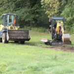 Zwei Kleinbagger tragen auf einer Wiese die Grasnarbe ab Zwei Kleinbagger tragen auf einer Wiese die Grasnarbe ab