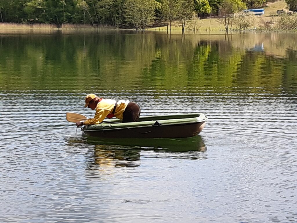 Eine Person lehnt sich über den Rand eines Bootes auf einem See