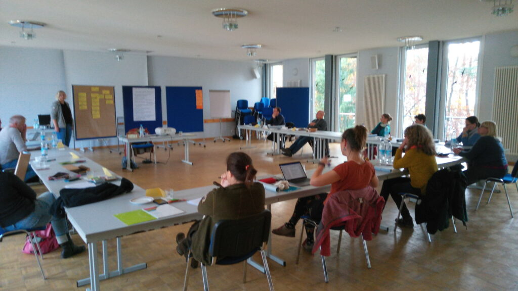 Tagungsraum mit ca. 10 Personen in U-Form an Tischen sitzend